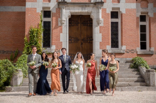 Bride groom bridesmaids and groomsmen walk in the sunshine together